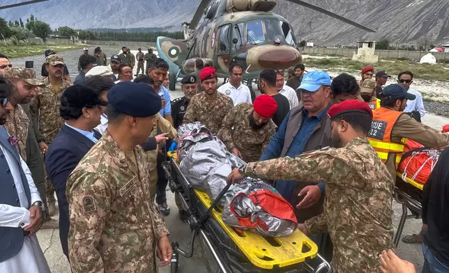 Pakistani army soldiers and volunteers prepare to load into ambulances, the bodies of climbers, that were recovered from Broad Peak nearly a week after an avalanche swept away a 10-member international expedition, upon arrival at a military base in Skardu, in northern Pakistan, Thursday, Aug. 6, 2026. (AP Photo/ M.H. Balti)