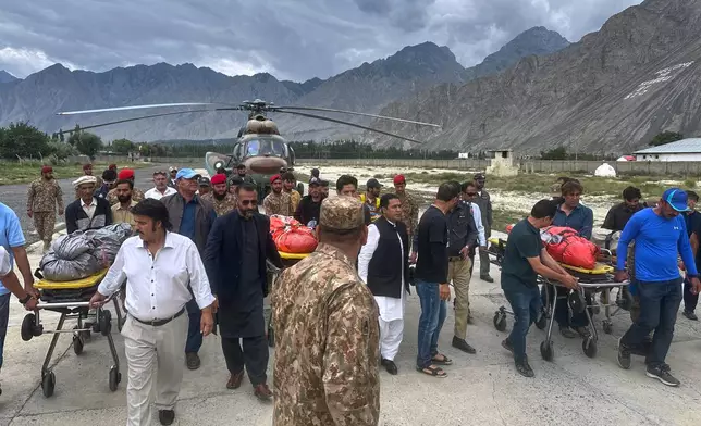 Pakistani army soldiers and volunteers prepare to load into ambulances, the bodies of climbers, that were recovered from Broad Peak nearly a week after an avalanche swept away a 10-member international expedition, upon arrival at a military base in Skardu, in northern Pakistan, Thursday, Aug. 6, 2026. (AP Photo/ M.H. Balti)