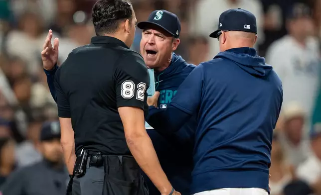 Seattle Mariners manager Dan Wilson, center, is held back by bench coach Manny Acta, right, while arguing with home plate umpire Emil Jimenez after getting thrown out of a baseball game against the Tampa Bay Rays in the sixth inning, Saturday, Aug. 8, 2026, in Seattle. (AP Photo/Stephen Brashear)