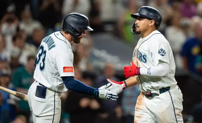 Seattle Mariners' Josh Naylor, right, is congratulated by Brendan Donovan after hitting a solo home run during the seventh inning of a baseball game against the Tampa Bay Rays, Saturday, Aug. 8, 2026, in Seattle. (AP Photo/Stephen Brashear)