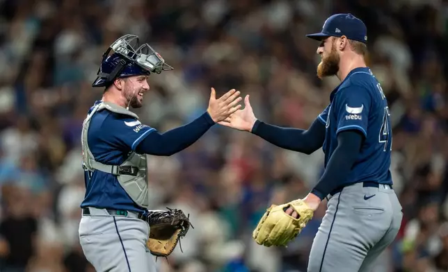 Tampa Bay Rays relief pitcher Bryan Baker, right, and catcher Liam Hicks celebrate after a baseball game against the Seattle Mariners, Saturday, Aug. 8, 2026, in Seattle. (AP Photo/Stephen Brashear)