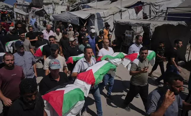 Mourners carry the flag-draped bodies of Palestinians, killed in Israeli strikes during the war with Hamas, whose remains were recently recovered from the rubble in Gaza City, Thursday, Aug. 20, 2026. (AP Photo/Jehad Alshrafi)