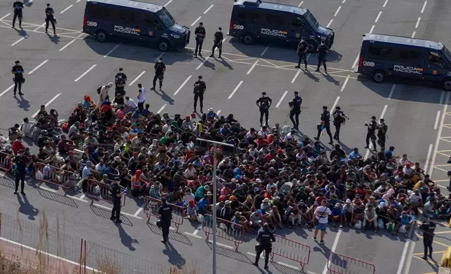 Migrants who crossed from Morocco into Spain are escorted by Spanish police to temporary shelters after being cleared from a beach in the Spanish exlave of Ceuta on Thursday, Aug. 20, 2026. (AP Photo/Antonio Sempere)