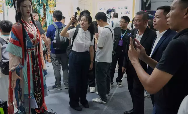 Visitors look at a humanoid robot wearing a traditional dress during the World Robot Conference in Beijing, Thursday, Aug. 20, 2026. (AP Photo/Achmad Ibrahim)