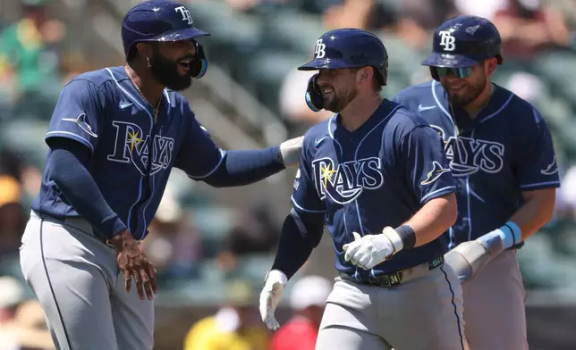 Tampa Bay Rays' Liam Hicks, middle, is congratulated by teammate Junior Caminero, left, after hitting a three-run home run during the fourth inning of a baseball game against the Athletics Wednesday, Aug. 12, 2026, in West Sacramento, Calif. (AP Photo/Scott Marshall)