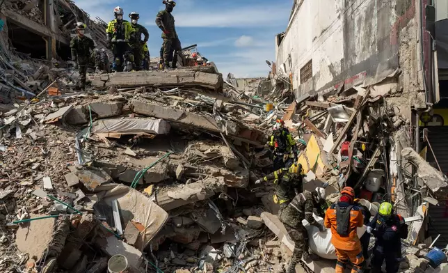 Rescuers carry the body of a victim from the rubble four days after after an earthquake hit Pereira, Colombia, Friday, Aug. 14, 2026. (AP Photo/Brandon Pinto)