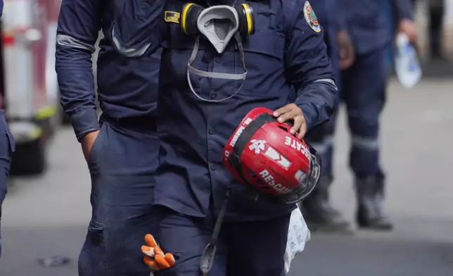 Firefighters walk to take a break from search-and-rescue efforts in Cali, Colombia, Friday, Aug. 14, 2026. (AP Photo/Ivan Valencia)
