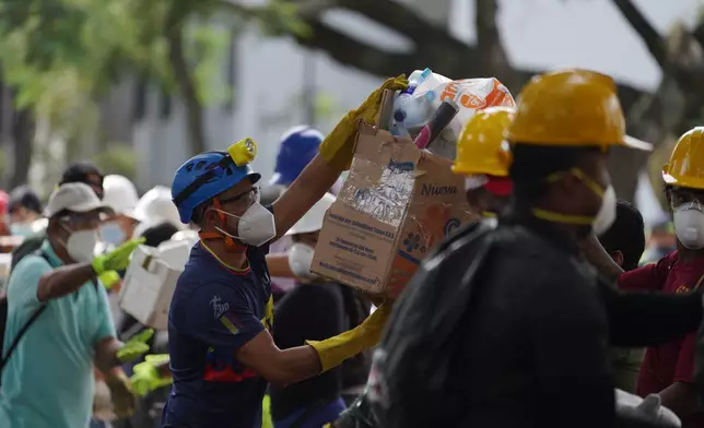 Rescuers pass food packages for rescue teams and volunteers searching through the rubble four days after an earthquake hit Cali, Colombia, Friday, Aug. 14, 2026. (AP Photo/Ivan Valencia)