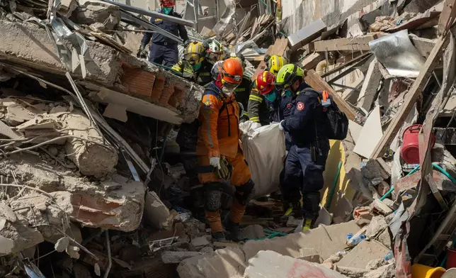 Rescuers carry the body of a victim from the rubble four days after after an earthquake hit Pereira, Colombia, Friday, Aug. 14, 2026. (AP Photo/Brandon Pinto)