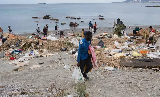 Migrants who crossed from Morocco into Spain gather their belongings after being cleared from the beach in the Spanish exlave of Ceuta, Thursday, Aug. 20, 2026. (AP Photo/Antonio Sempere)