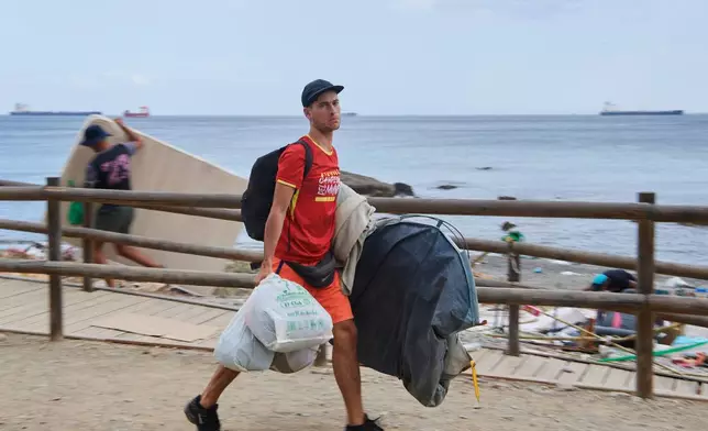 A migrant who crossed from Morocco into Spain gathers his belongings after being cleared from the beach in the Spanish exlave of Ceuta, Thursday, Aug. 20, 2026. (AP Photo/Antonio Sempere)