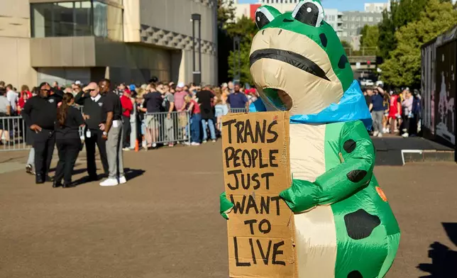 A man dressed in a frog costume holds a sign supporting trans people during a rally to support Indiana Fever guard Sophie Cunningham after her comments on transgender athletes in women's sports before a WNBA basketball game between the Portland Fire and the Indiana Fever in Portland, Ore., Friday, July 31, 2026. (AP Photo/Craig Mitchelldyer)