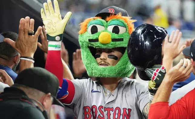 Boston Red Sox's Jarren Duran is congratulated in the dugout after hitting a grand slam during the eleventh inning of a baseball game against the Miami Marlins, Tuesday, Aug. 25, 2026, in Miami. (AP Photo/Lynne Sladky)
