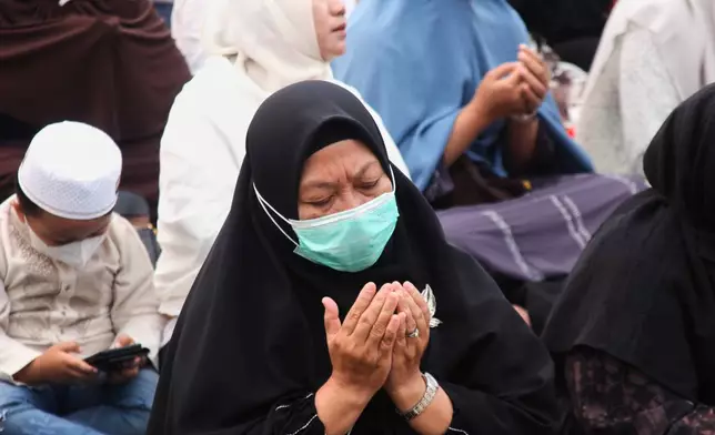A woman prays during a prayer requesting for rain following wildfires that burn through peatlands in several regions in Sumatra and Kalimantan Island, in Palembang, South Sumatra, Indonesia, Tuesday, Aug. 25, 2026. (AP Photo/Muhammad Fajri)