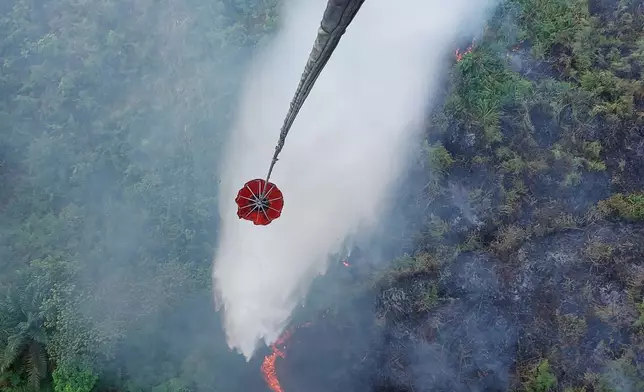 In this photo released by Jambi Regional Disaster Mitigation Agency (BPBD Jambi), a helicopter conducts a water bombing to extinguish wildfire burning through a peatland field in Danau Lamo, Jambi province, Indonesia, on Monday, Aug. 24, 2026. (BPBD Jambi via AP)