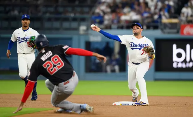 Los Angeles Dodgers second baseman Miguel Rojas (72) turns a double play over the slide by Washington Nationals' James Wood during the first inning of a baseball game in Los Angeles, Sunday, Sept. 6, 2026. Dylan Crews was out at first. (AP Photo/Kyusung Gong)