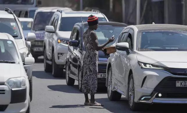 Acrobats collect contributions from motorists after a short performance in a busy street amid by traffic in Nairobi, Kenya, Wednesday, Aug. 26, 2026. (AP Photo/Brian Inganga)