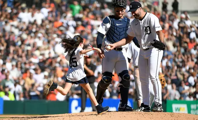 Genevieve Verlander, left, runs to hug her dad, Detroit Tigers starting pitcher Justin Verlander, right, as catcher Dillon Dingler looks on during the sixth inning of a baseball game against the Pittsburgh Pirates, Saturday, Sept. 26, 2026, in Detroit. (AP Photo/Jose Juarez)