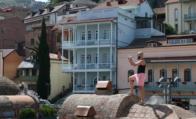 A 28-year-old digital content marketer who recently moved out of Russia takes photos in the Old Town in Tbilisi, Georgia, Saturday, Sept. 5, 2026. He asked not to be identified because of security concerns. (AP Photo/Zurab Tsertsvadze)