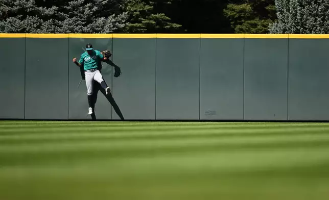 Seattle Mariners center fielder Julio Rodríguez slams into the wall after catching a fly ball in the fourth inning against the Colorado Rockies during a baseball game Sunday, Sept. 20, 2026, in Denver. (AP Photo/RJ Sangosti)