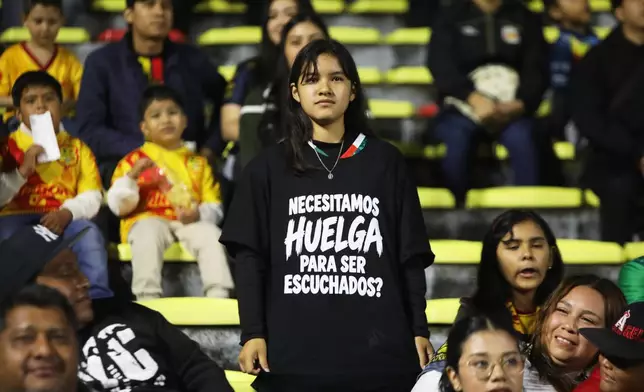 A fan shows her T-shirt bearing the message, "Do we need a strike to be heard?", before a Mexican second-division soccer match between Atletico Morelia and Leones Negros in Morelia, Michoacan state, Mexico, Saturday, Sept. 19, 2026. (AP Photo/Armando Solis)