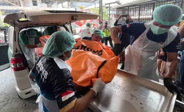 In this photo taken with a smartphone, staff remove the body of a victim of a passenger ferry that overturned in bad weather in the Java Sea from an ambulance upon arrival at a hospital in Banjarmasin, South Kalimantan, Indonesia, Tuesday, Sept. 15, 2026. (AP Photo/Iman Satria)