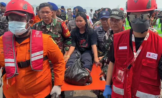 In this photo taken with a smartphone, rescuers carry a survivor from a passenger ferry overturned in bad weather in the Java Sea on a stretcher upon arrival at a port in Banjarmasin, South Kalimantan, Indonesia, Tuesday, Sept. 15, 2026. (AP Photo/Iman Satria)