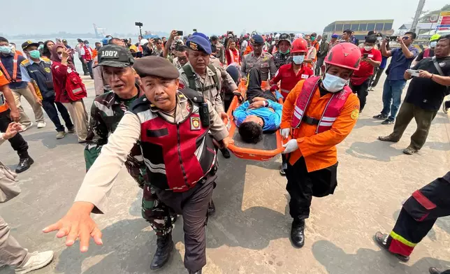 In this photo taken with a smartphone, rescuers carry a survivor from a passenger ferry overturned in bad weather in the Java Sea on a stretcher upon arrival at a port in Banjarmasin, South Kalimantan, Indonesia, Tuesday, Sept. 15, 2026. (AP Photo/Iman Satria)