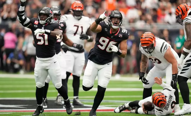 Houston Texans defensive end Logan Hall (96), and defensive end Will Anderson Jr. (51), celebrate after sacking Cincinnati Bengals quarterback Joe Burrow (9), bottom right, during the first half of an NFL football game in Houston, Sunday, Sept. 20, 2026. (AP Photo/Ashley Landis)