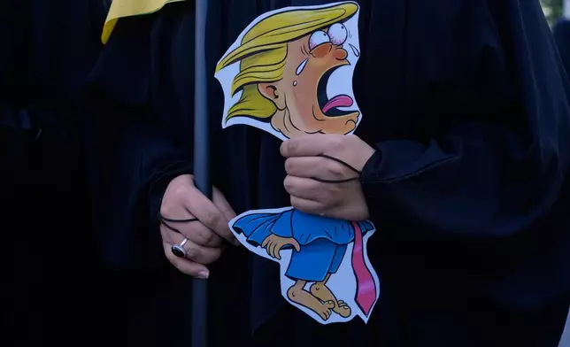A woman holds a caricature of U.S. President Donald Trump as she attends the state-organized "Janfada," or "Sacrifice for Iran," military-style parade in Tehran, Iran, Friday, Sept. 18, 2026. (AP Photo/Vahid Salemi)