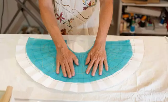 Silvia Ramos López, owner of Manos de Agua, makes a handmade fan at her workshop in Seville, Spain, on Aug. 25, 2026. (AP Photo/Laura Leon)