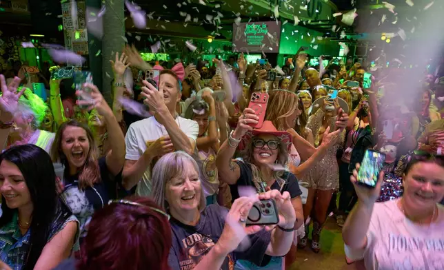 People celebrate at a bar on Broadway as the song "9 to 5" is performed during a Dolly Parton Day event honoring the late country music artist, Friday, Sept. 25, 2026, in Nashville, Tenn. (AP Photo/George Walker IV)