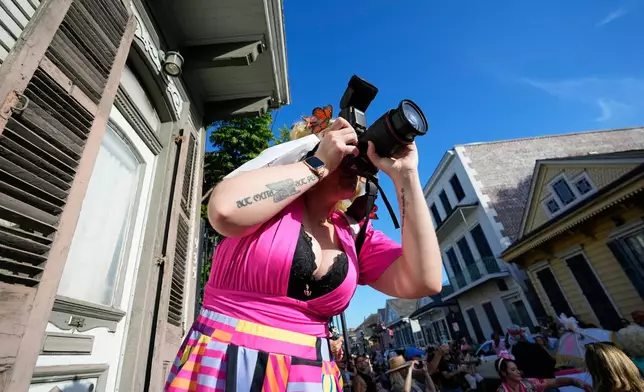 A person takes photos as members of the Krewe of Dolly lead a second line parade in commemoration of the life of Dolly Parton through the French Quarter Friday, Sept. 25, 2026, in New Orleans. (AP Photo/Gerald Herbert)