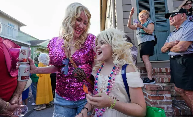 Adrienne Hery and her daughter June Hery, 9, watch as members of the Krewe of Dolly lead a second line parade in commemoration of the life of Dolly Parton through the French Quarter Friday, Sept. 25, 2026, in New Orleans. (AP Photo/Gerald Herbert)
