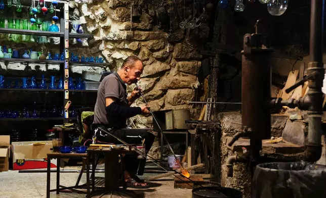 Palestinian glassblower Yaqoub Al-Natsheh makes a glass pitcher at his shop in the West Bank city of Hebron, Monday, Sept. 14, 2026. (AP Photo/Mahmoud Illean)