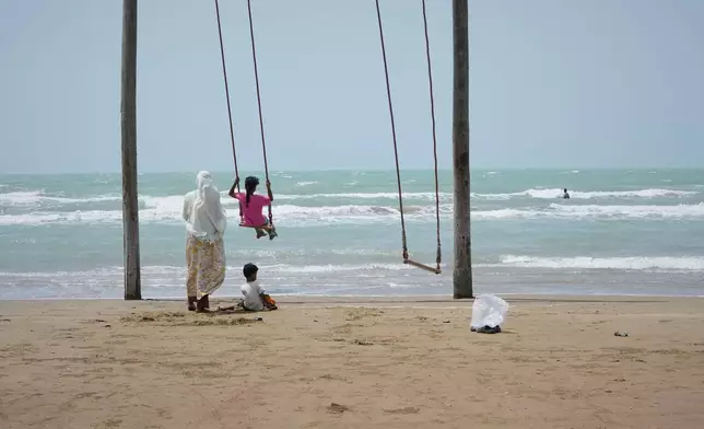 A woman pushes a girl on a swing on a beach along the Strait of Hormuz in Kuhestak, Iran, Friday, Sept. 4, 2026. (AP Photo/Vahid Salemi)