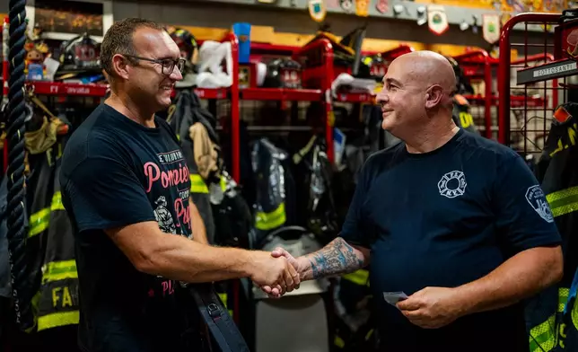 Firefighter Sal Argano, right, Ladder 10, greets Laurent Cosenefroy, a volunteer firefighter from France visiting New York and the FDNY "Ten House" for his birthday, Friday, Aug. 7, 2026, in New York. (AP Photo/Angelina Katsanis)