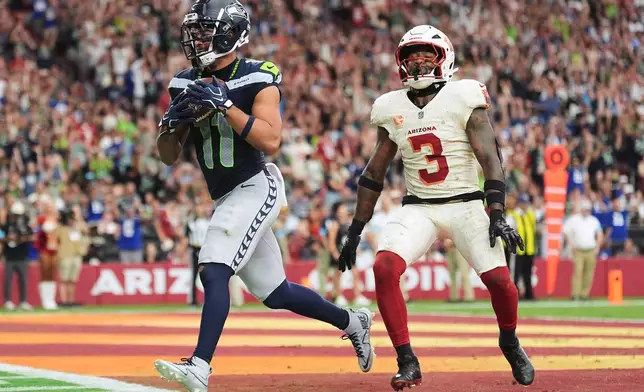 Seattle Seahawks wide receiver Jaxon Smith-Njigba, left, scores a touchdown against Arizona Cardinals safety Budda Baker, right, during the second half of an NFL football game in Glendale, Ariz., Sunday, Sept. 20, 2026. (AP Photo/Ross D. Franklin)