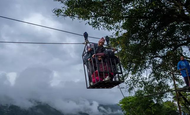 Residents commute across the Trishuli river on a newly installed zipline in the aftermath of flash floods at Bidur in Nepal's Nuwakot district, Nepal, Wednesday, Sept. 2, 2026. (AP Photo/Rajesh Kumar Singh)
