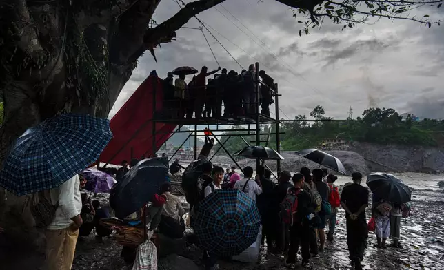 Residents wait for their turn commute across the Trishuli river on a newly installed zipline in the aftermath of flash floods at Bidur in Nepal's Nuwakot district, Nepal, Wednesday, Sept. 2, 2026. (AP Photo/Rajesh Kumar Singh)