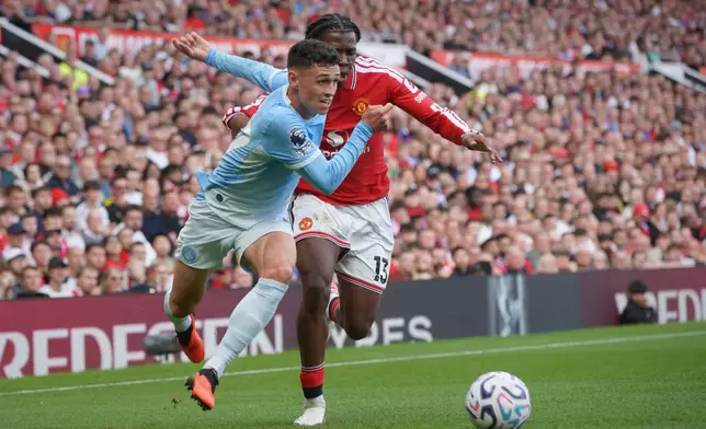 Manchester City's Phil Foden, left, challenges for the ball with Manchester United's Patrick Dorgu during the English Premier League soccer match between Manchester United and Manchester City in Manchester, England, Sunday, Sept. 13, 2026. (AP Photo/Ian Hodgson)
