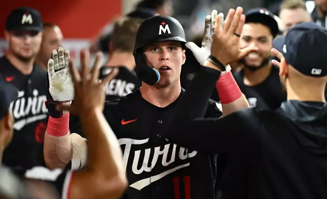 Minnesota Twins' Walker Jenkins, center, is greeted by teammates after hitting a home run during the seventh inning of a baseball game against the Los Angeles Angels, Friday, Sept. 18, 2026, in Anaheim, Calif. (AP Photo/William Liang)