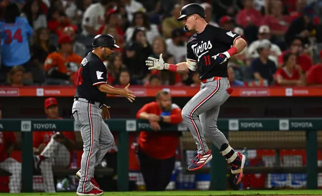 Minnesota Twins' Walker Jenkins (11) is greeted by third base coach Ramon Borrego, left, after hitting a home run during the seventh inning of a baseball game against the Los Angeles Angels, Friday, Sept. 18, 2026, in Anaheim, Calif. (AP Photo/William Liang)