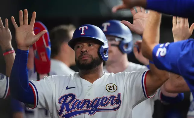 Texas Rangers' Elias DÌaz is greeted in the dugout after he and teammate Danny Jansen-, back, scored on a bases loaded single by teammate Corey Seager against the Boston Red Sox during the second inning of a baseball game Tuesday, Sept. 15, 2026, in Arlington, Texas. (AP Photo/Julio Cortez)