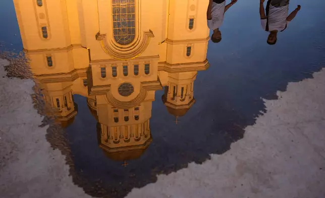 The National Cathedral is reflected in a puddle as youth gather for the Procession of Lights, part of a four-day program of the International Meeting of Orthodox Youth (ITO), in Bucharest, Romania, Wednesday, Sept. 2, 2026. (AP Photo/Andreea Alexandru)
