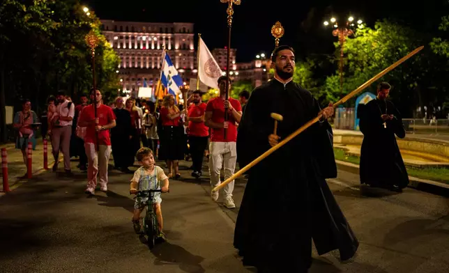 A child rides a bicycle next to priests leading the Procession of Lights, part of a four-day program of the International Meeting of Orthodox Youth (ITO), in Bucharest, Romania, Wednesday, Sept. 2, 2026. (AP Photo/Andreea Alexandru)