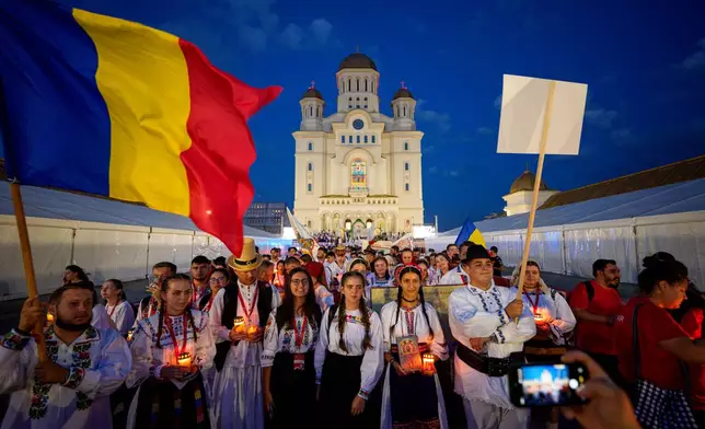 Youngsters wearing traditional outfits pose backdropped by the National Cathedral before the Procession of Lights, part of a four-day program of the International Meeting of Orthodox Youth (ITO), in Bucharest, Romania, Wednesday, Sept. 2, 2026. (AP Photo/Andreea Alexandru)