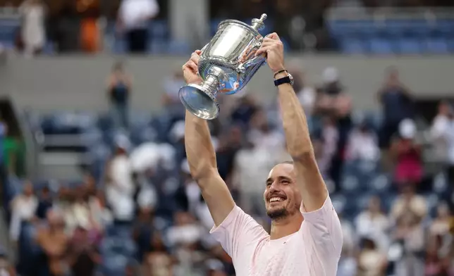 Alexander Zverev, of Germany, poses with the trophy after he won the men's singles final of the U.S. Open tennis championships against Ben Shelton, of the United States, Sunday, Sept. 13, 2026, in New York. (AP Photo/Adam Hunger)