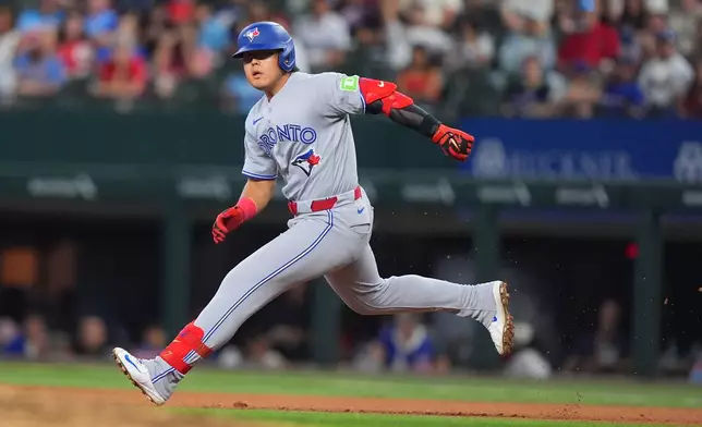 Toronto Blue Jays' Kazuma Okamoto, of Japan, rounds first base after hitting a single, scoring teammate Brett Bateman, during the fifth inning of a baseball game against the Texas Rangers, Sunday, Sept. 20, 2026, in Arlington, Texas. (AP Photo/LM Otero)