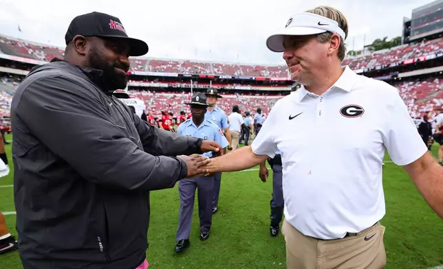 Western Kentucky assistant coach David Metcalf, left, embraces Georgia head coach Kirby Smart, right, after an NCAA college football game, Saturday, Sept. 12, 2026, in Athens, Ga. (AP Photo/Colin Hubbard)